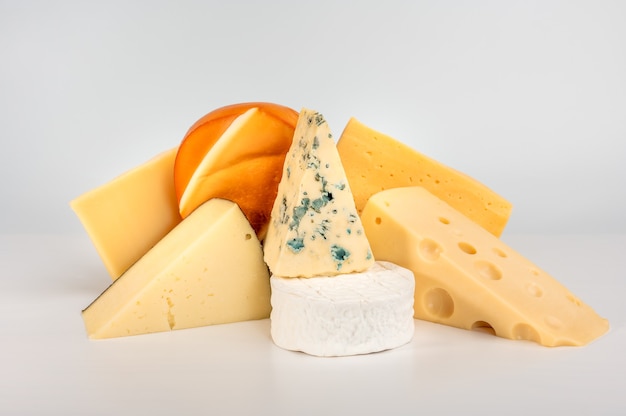Diversi tipi di delizioso formaggio su sfondo bianco. gorgonzola Dorblu, Suluguni affumicato, Brie, Maasdam, Cheddar, Parmigiano.
