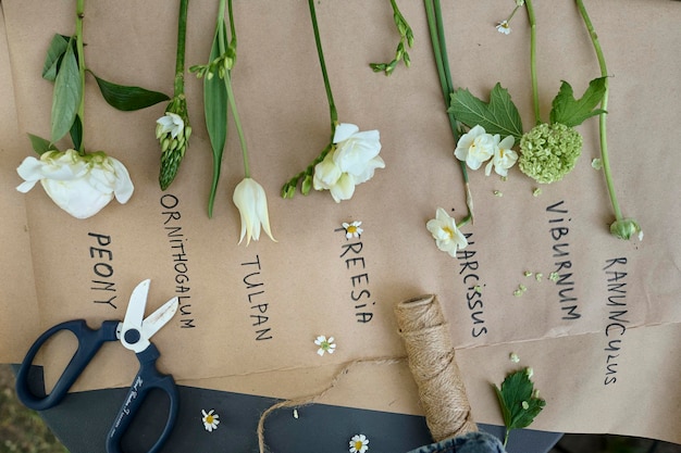 Diversi tipi di fiori bianchi disposti su carta pergamena su un tavolo in giardino