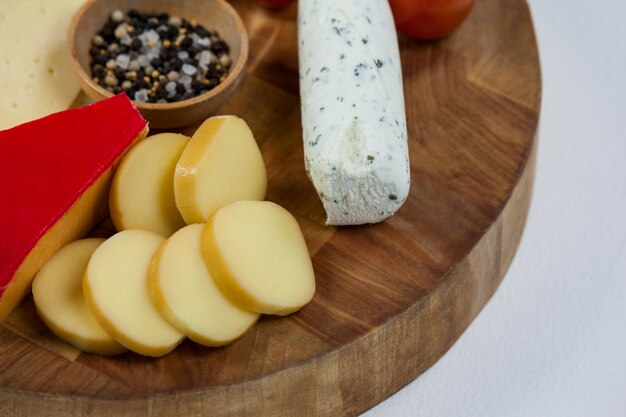 Diversi tipi di formaggio, pomodorini, spezie e marmellata su tavola di legno