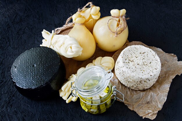 Diversi tipi di formaggio su uno sfondo nero. Piatto di formaggi