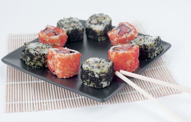 diversi tipi di Maki sushi e bacchette su un piatto nero