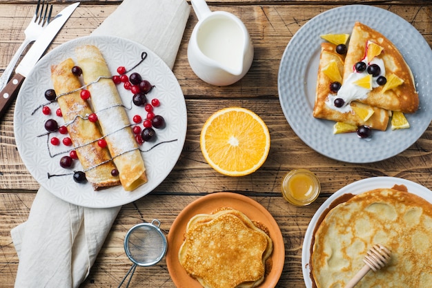 Diversi tipi di pancake con frutti di bosco su un tavolo di legno