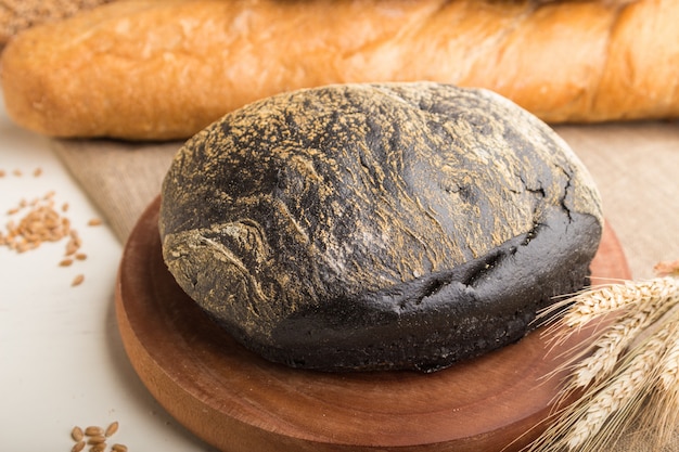 Diversi tipi di pane appena sfornato su una parete di legno bianca. vista laterale, messa a fuoco selettiva.