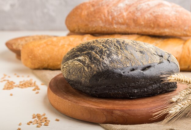 Diversi tipi di pane appena sfornato su una superficie di legno bianca