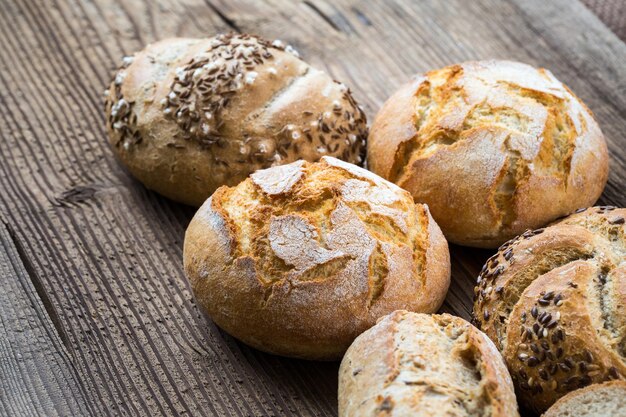 Diversi tipi di pane fresco su tavola di legno Assortimento isolato di pane su sfondo marrone