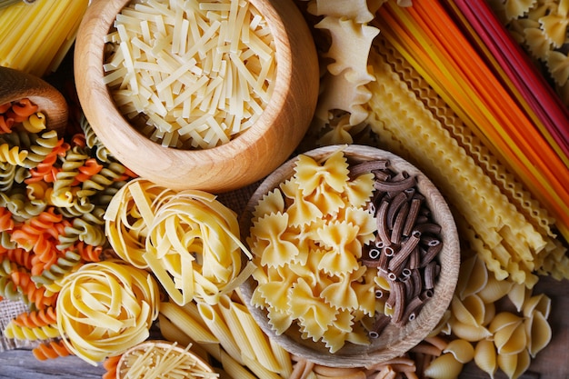 Diversi tipi di pasta con ciotole di legno sul tavolo, vista macro