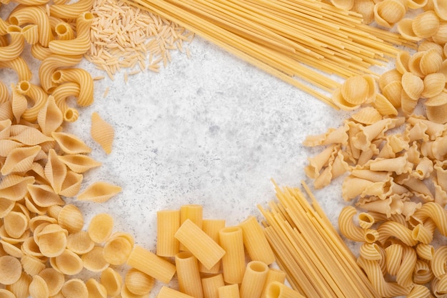 Diversi tipi di pasta cruda su uno sfondo di tessuto