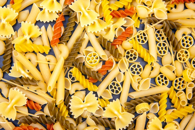 Diversi tipi di pasta italiana colorati su sfondo scuro