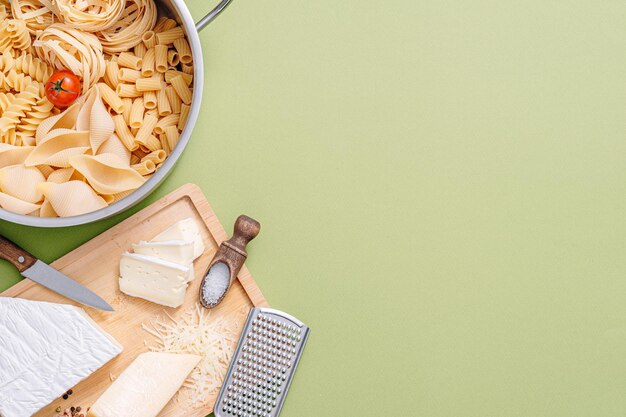 Diversi tipi di pasta italiana su fondo di legno con vari ingredienti per cucinare piatti della tradizione italiana