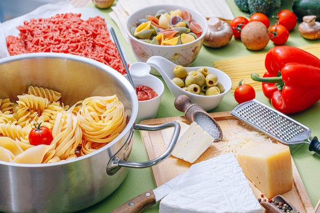 Diversi tipi di pasta italiana su fondo di legno con vari ingredienti per cucinare piatti della tradizione italiana