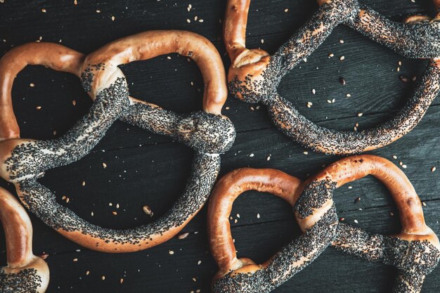 Diversi tipi di pretzel al forno con semi su sfondo nero