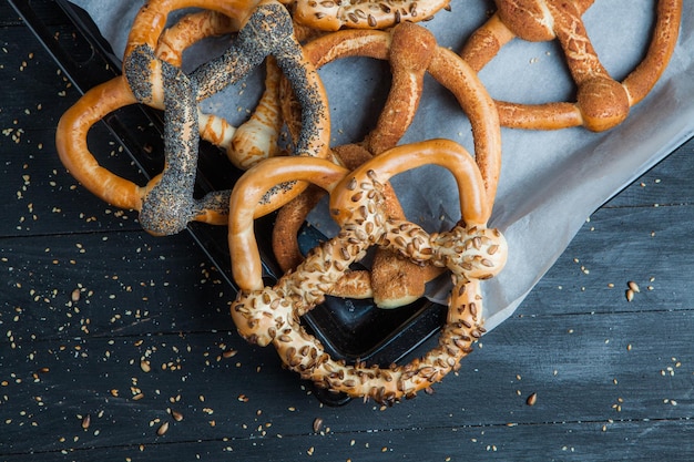 Diversi tipi di pretzel al forno o bagel con semi su sfondo nero