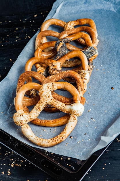 Diversi tipi di pretzel al forno o bagel con semi su sfondo nero