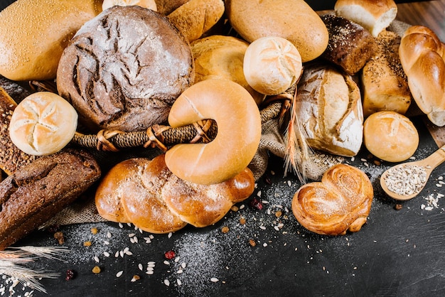 Diversi tipi di prodotti da forno freschi e pane su fondo di legno nero Vista dall'alto Spazio di copia