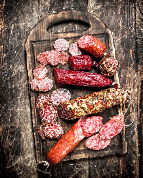 Diversi tipi di salame sulle tavole. Su uno sfondo di legno.