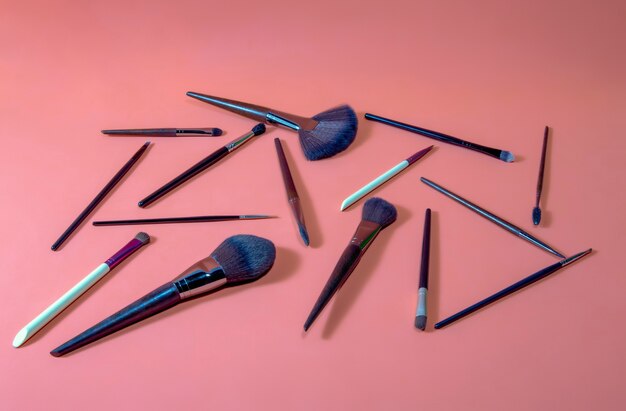 Diversi tipi e dimensioni di pennelli da trucco professionali su sfondo arancione