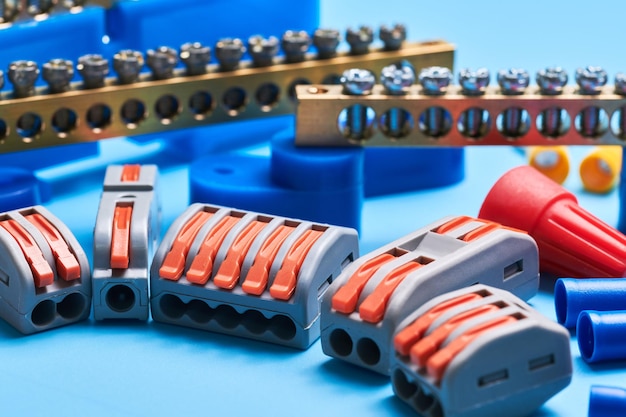 Diversi utensili elettrici isolati su sfondo blu apparecchiature per elettricisti cavi terminali connettori fusibili interruttori