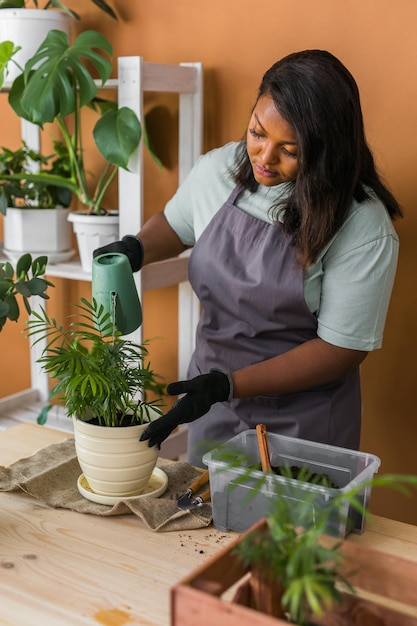 Diversità afroamericana donna e vaso con pianta felice lavoro in giardino interno o accogliente ufficio domestico