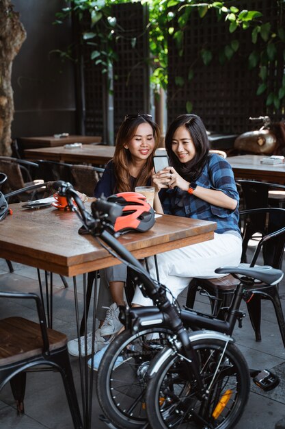 Divertendosi donna asiatica che gode della chiacchierata e che per mezzo dello smartphone quando una pausa al caffè