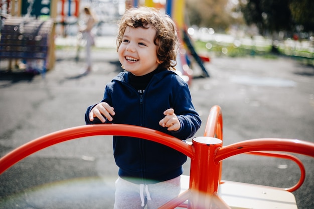 Divertente carino felice bambino giocando nel parco giochi. L'emozione di felicità, divertimento, gioia. Sorriso di un bambino.