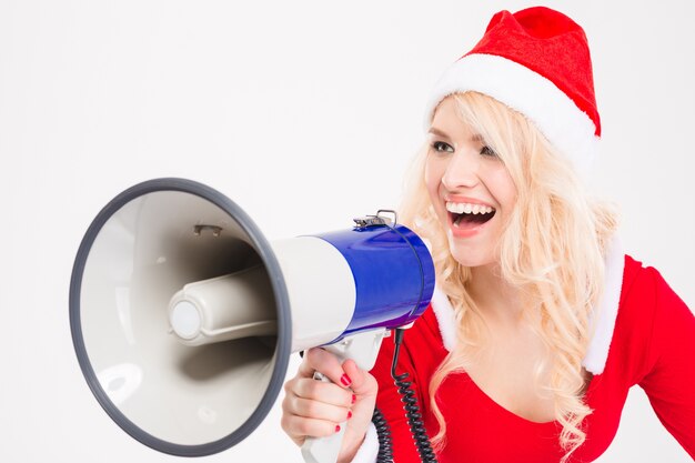 Divertente divertente donna bionda in costume di babbo natale e cappello urlando in altoparlante su sfondo bianco