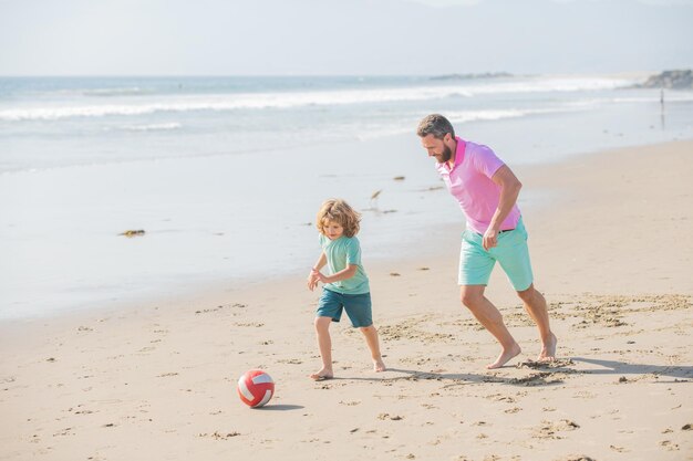 Divertente famiglia di papà e bambino che giocano a palla sulla spiaggia genitorialità