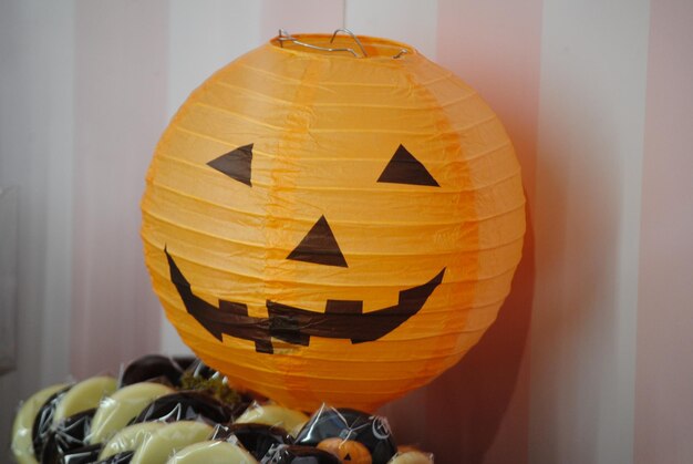 Divertente lanterna di carta a forma di zucca sorridente e cioccolatini che mostra idee per Halloween