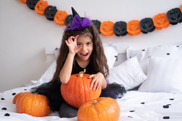 Divertente ragazza araba in costume da strega che si diverte a decorare la camera da letto di halloween.