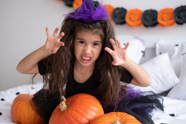 Divertente ragazza araba in costume da strega che si diverte a decorare la camera da letto di halloween.