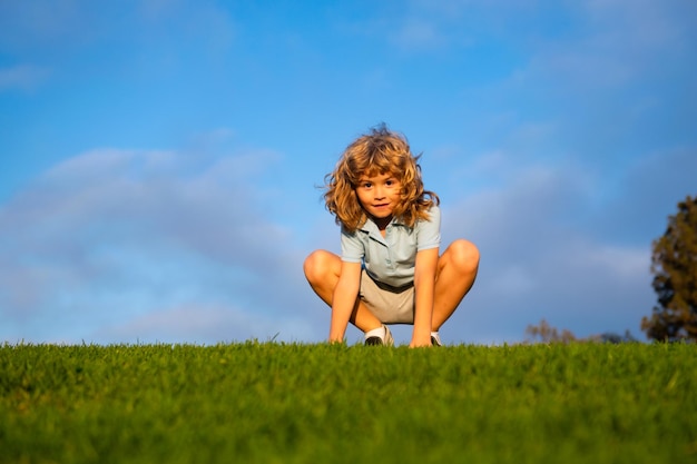 Divertente ragazzo dai capelli rossi che gioca sull'erba verde nel parco bambini felici dell'infanzia stile di vita attivo all'aperto