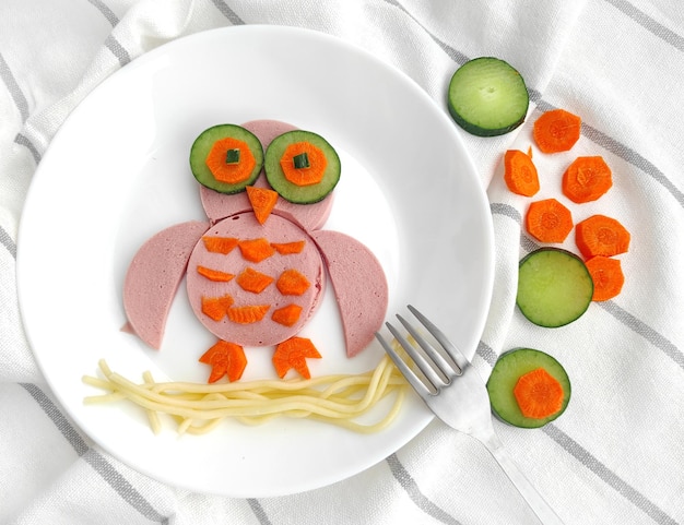 Divertente uccello gufo commestibile a base di salsiccia, carote, cetrioli per colazione per bambini.