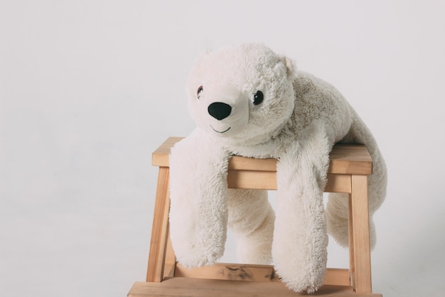 Divertente vecchio giocattolo bianco orso polare sulla sedia di legno