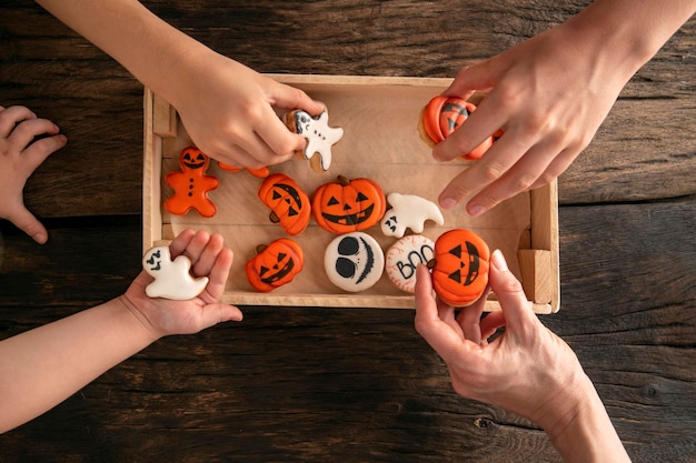 Divertenti deliziosi biscotti allo zenzero per Halloween sul tavolo Le mani prendono i biscotti Biscotti di pan di zenzero di Halloween nella scatola