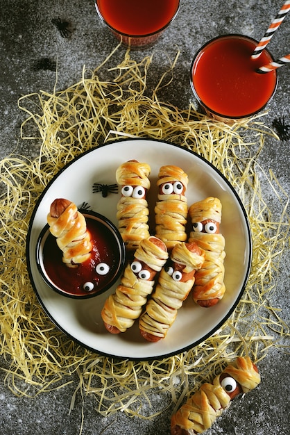 Divertenti mummie di salsiccia nell'impasto con ketchup per la festa di Halloween