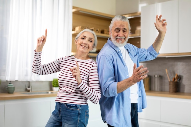 Divertimento domestico gioiosi coniugi senior che ballano insieme nell'interno della cucina