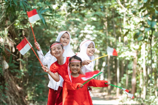 Divertirsi con un gruppo di bambine asiatiche tenendo la bandiera rossa e bianca e alzando insieme la bandiera