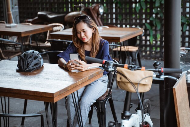 Divertirsi donna asiatica che usando smartphone quando una pausa al caffè