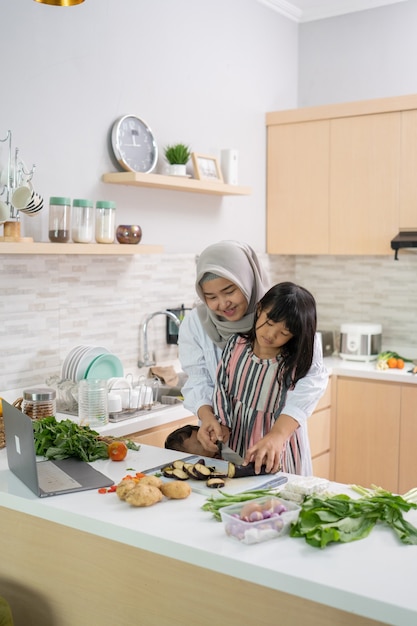 Divertirsi donna musulmana con hijab e bambino che prepara la cena insieme