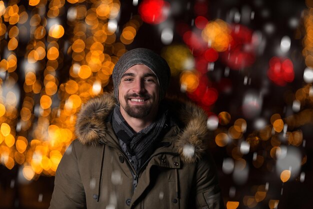 Divertirsi in una fata di Natale Giovane uomo allegro vestito caldo è in piedi nel mercato delle vacanze