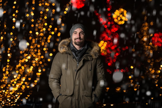 Divertirsi in una fata di Natale Giovane uomo allegro vestito caldo è in piedi nel mercato delle vacanze