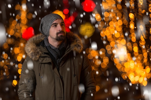 Divertirsi in una fata di Natale Giovane uomo allegro vestito caldo è in piedi nel mercato delle vacanze