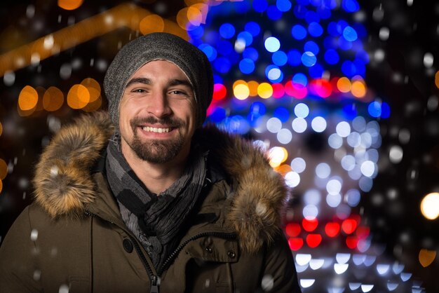 Divertirsi in una fata di Natale Giovane uomo allegro vestito caldo è in piedi nel mercato delle vacanze