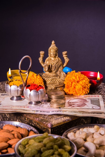 Diwali e preparazione per Laxmi o Lakshmi Pooja con elementi come diya, banconote, dolci, fiori, snack, haldi e kumkum