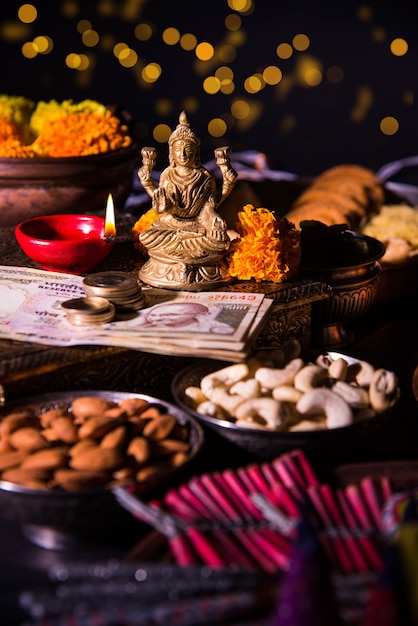 Diwali e preparazione per Laxmi o Lakshmi Pooja con elementi come diya, banconote, dolci, fiori, snack, haldi e kumkum