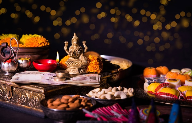 Diwali e preparazione per Laxmi o Lakshmi Pooja con elementi come diya, banconote, dolci, fiori, snack, haldi e kumkum