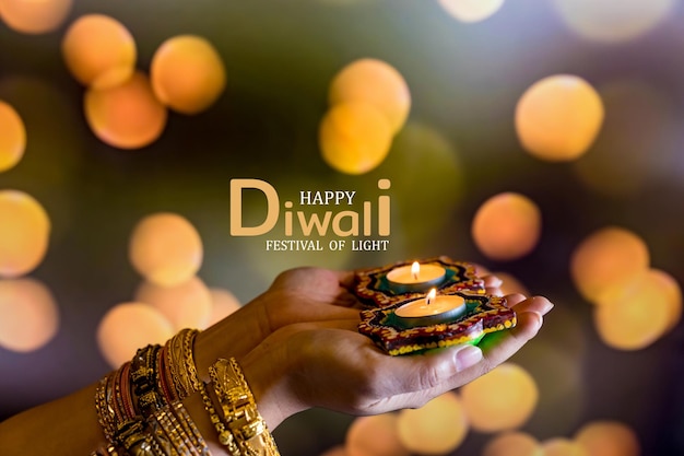 Diwali felice - Mani della donna con la candela accesa della tenuta dell'henné isolata su fondo scuro. Le lampade di Clay Diya si sono accese durante Dipavali, festa indù della celebrazione delle luci. Copia spazio per il testo.