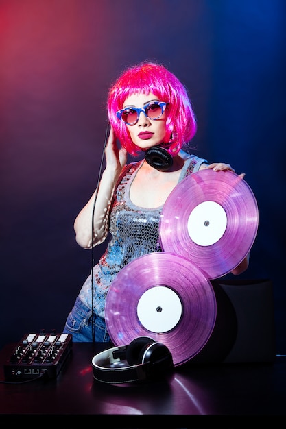 DJ con cuffie, capelli rosa e dischi in vinile rosa