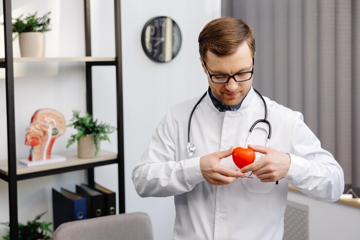 Doctor in white coat and glasses holding a red heart at hospital office Medical health care and doctor staff service concept