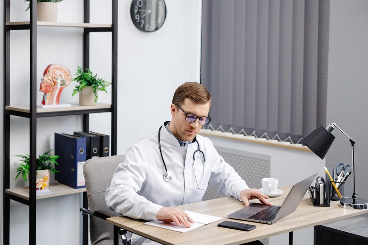 Doctor man sitting at the desk at his working place and working on laptop Perfect medical service in clinic Happy future of medicine and healthcare
