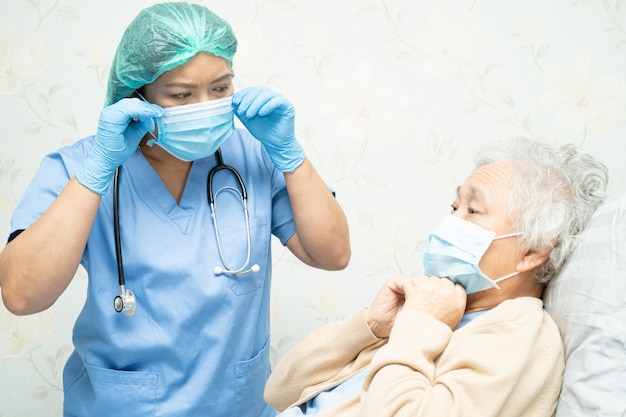 Doctor teching Paziente donna asiatica senior che indossa una maschera in ospedale per proteggere il coronavirus Covid-19.